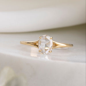 Gold ring with a clear gemstone on a light background