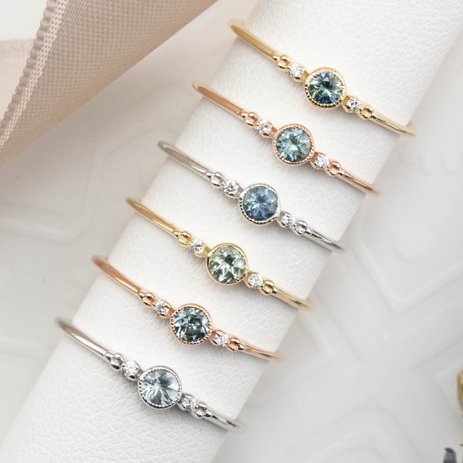 Seven Dainty Estel Bezel Ring featuring a 0.18ct round blue-green Montana sapphire in 14k gold