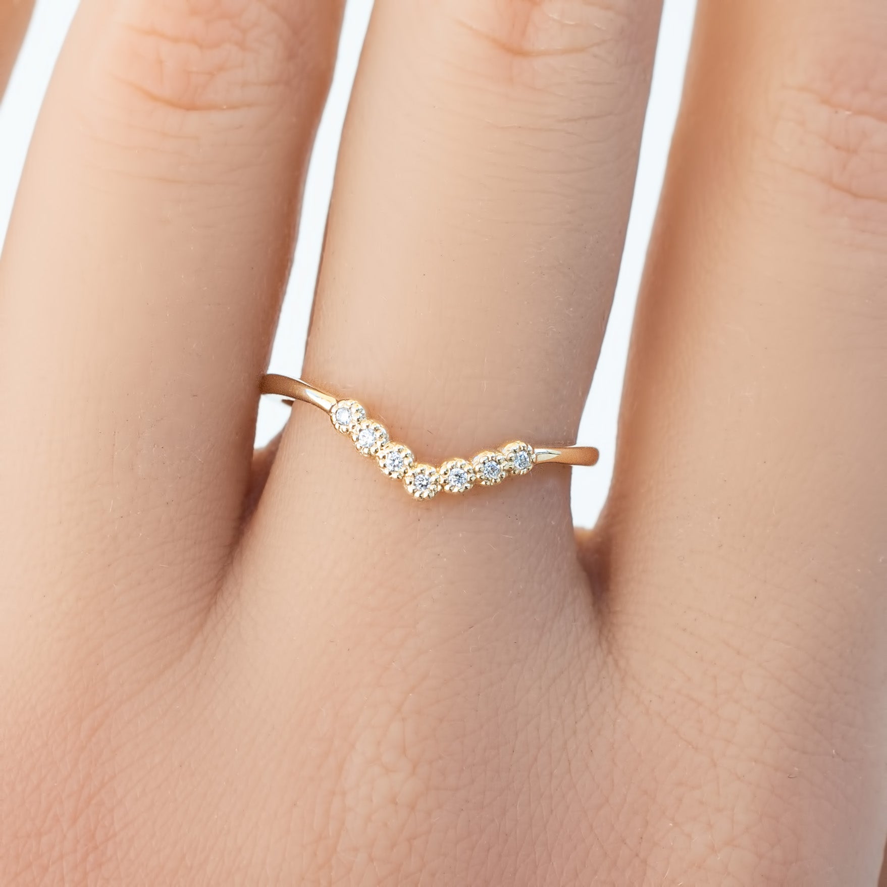 Close-up of a gold Dahlia Curved Ring with natural white diamonds on a hand, elegant V-shaped band design