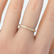 Close-up of a solid gold Hazel Eternity Ring with natural white diamonds on a finger, ethical and recyclable packaging.