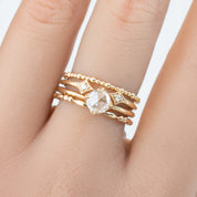 Close-up of a hand wearing the Adina Ring, a 1.5mm ethically sourced solid gold full eternity bead ring with diamonds.