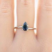 1.06ct pear-shaped dark blue Montana sapphire ring on finger with deep navy blue color and silver band