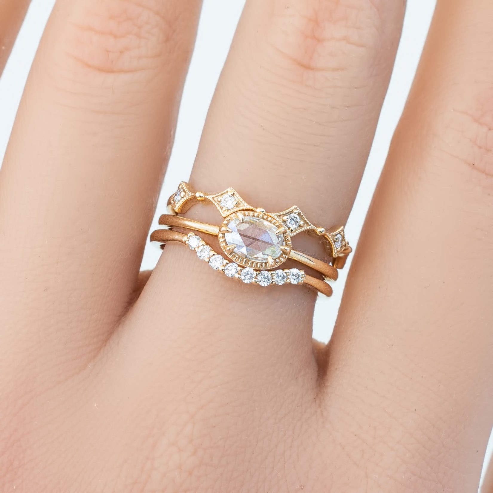 Close-up of a hand wearing a gold Star Diamond Eternity Ring with white diamonds and a central oval gemstone