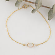 Gold bracelet with a central gemstone on a light background