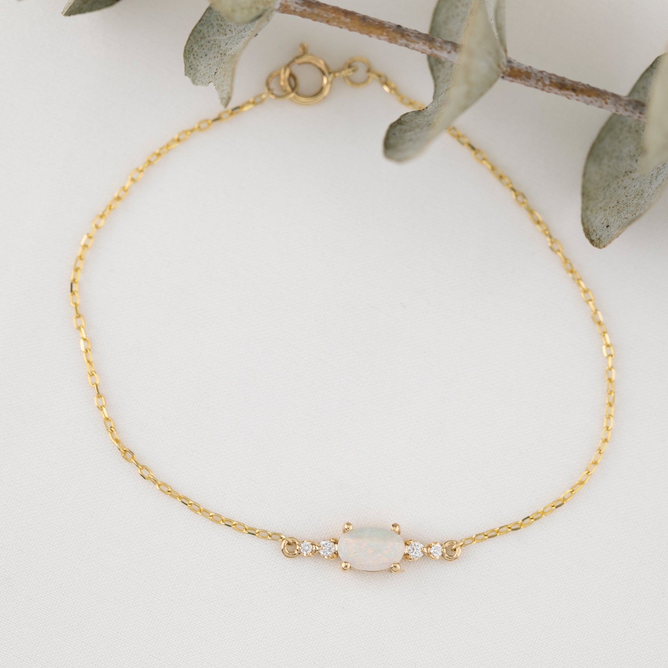 Gold bracelet with a central gemstone on a light background