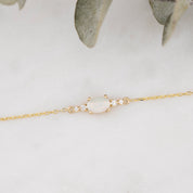 Gold bracelet with a central gemstone on a light gray background
