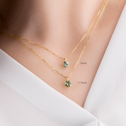Two gold necklaces with green gemstones on a white background