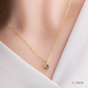 Gold necklace with a green gemstone pendant on a white background