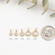 Gold hoop earrings with varying sizes next to a quarter for scale on a white background.