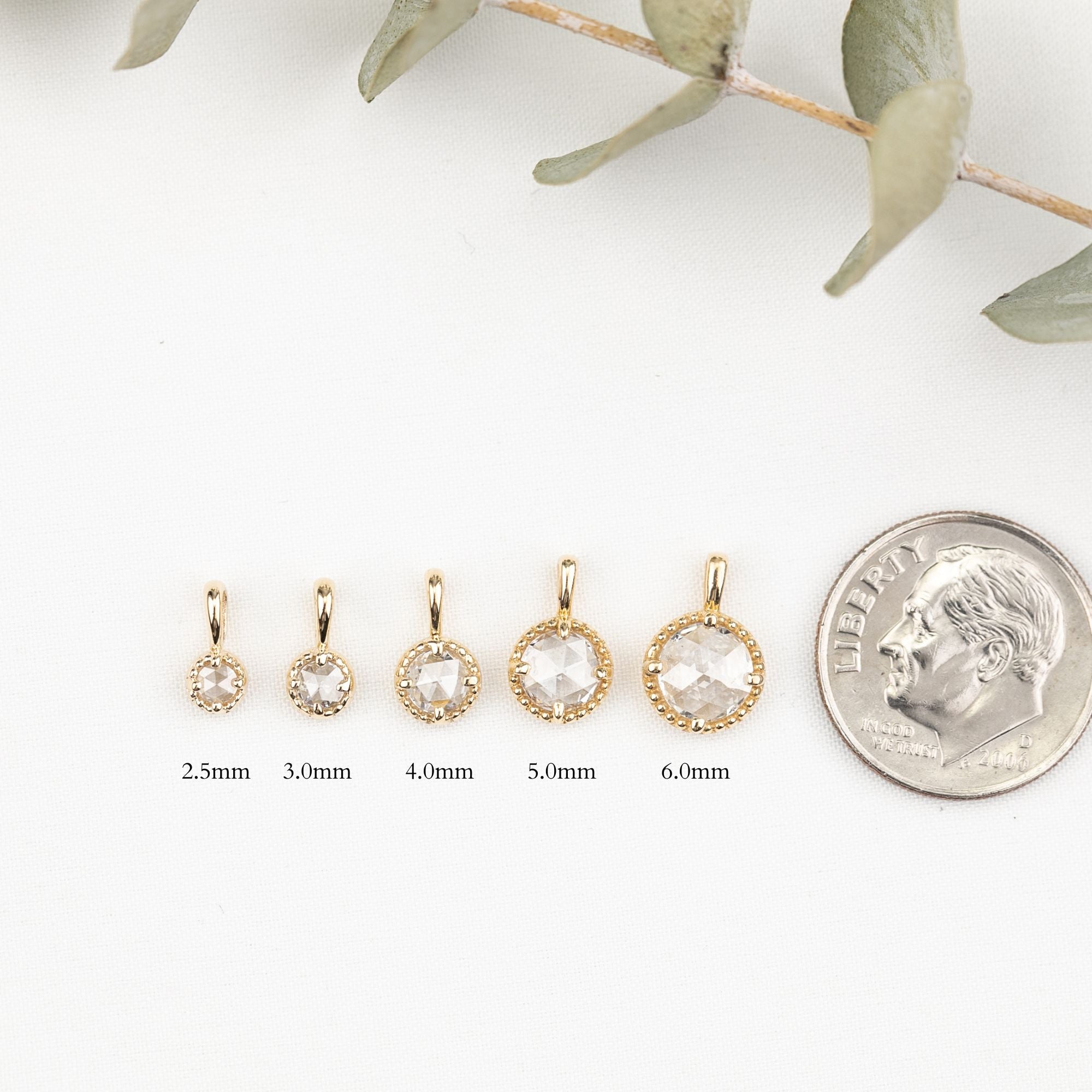Gold hoop earrings with varying sizes next to a quarter for scale on a white background.