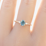 Estel Ring featuring an oval 0.85ct oval teal Montana sapphire with natural diamond accents in 14k yellow gold on the finger