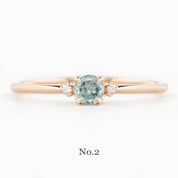 Rose gold ring with a green gemstone on a white background