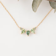 Gold necklace with green gemstones on a white background