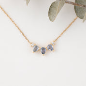 Gold necklace with three teardrop-shaped gemstones on a light background