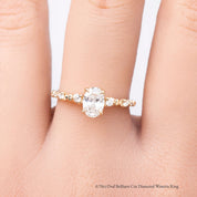 gold ring with a 0.7ct diamond on a person's finger against a white background