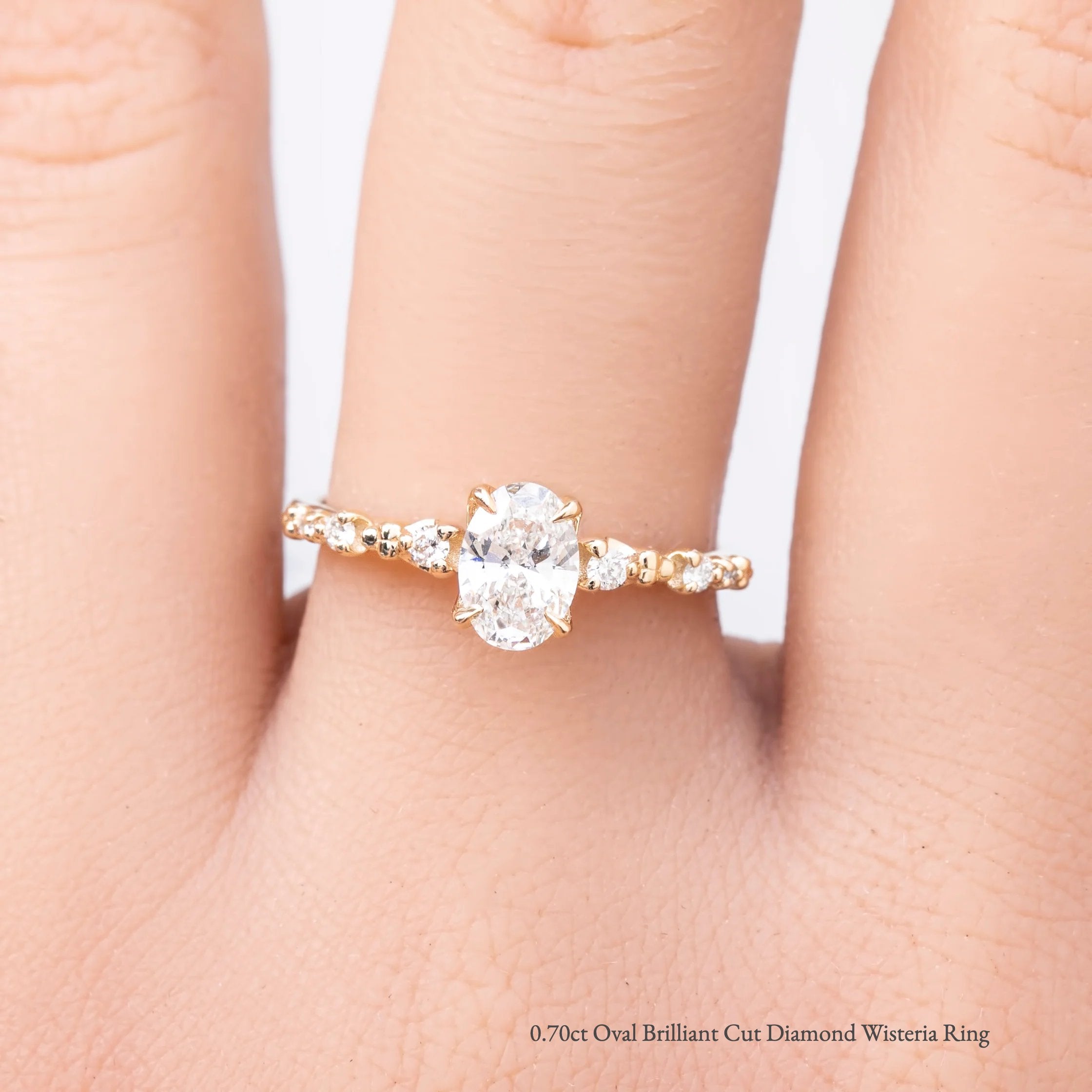 gold ring with a 0.7ct diamond on a person's finger against a white background