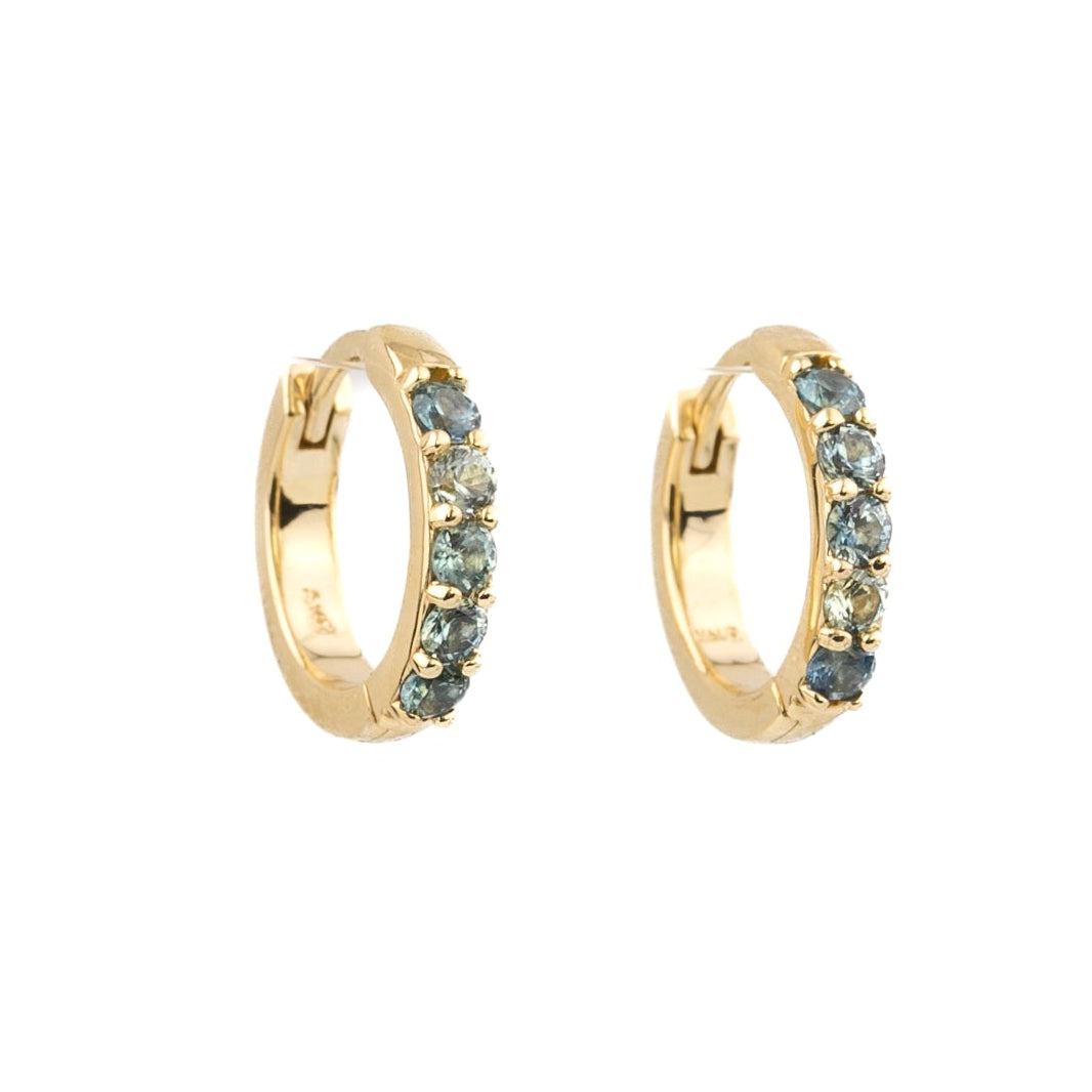 A pair of gold huggie hoop earrings embellished with small round blue-gray stones, shown against a plain white background.