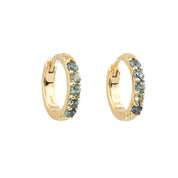 A pair of gold huggie hoop earrings embellished with small round blue-gray stones, shown against a plain white background.