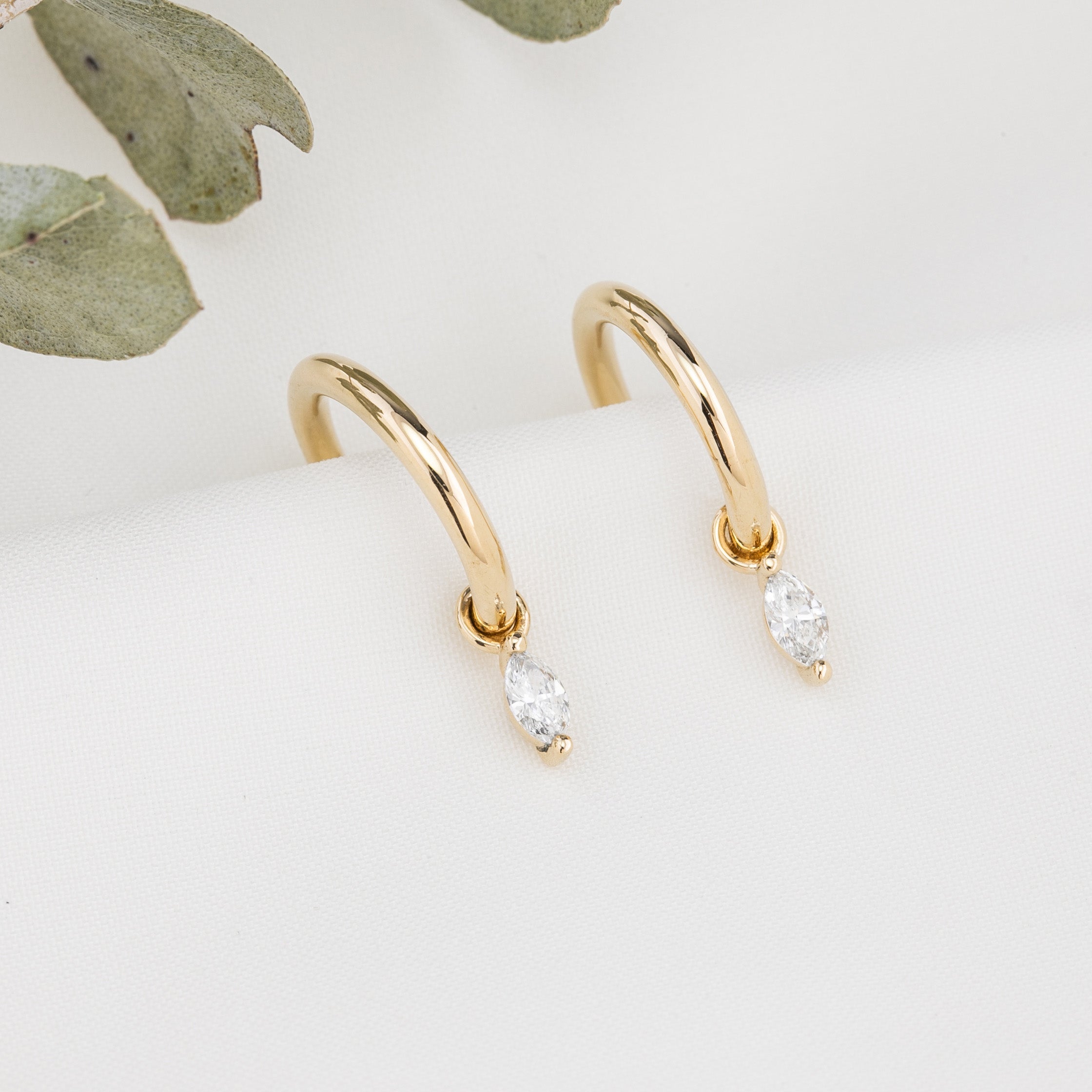 Gold hoop earring with measurements of appx 13.5mm diameter on a white background