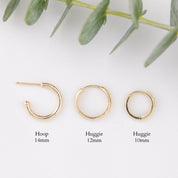 Three gold hoop earrings shown on a white background with green leaves at the top and size labels below: hoop 14mm, huggie 12mm, and huggie 10mm.