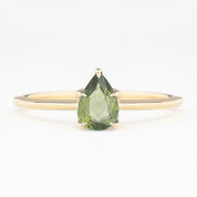 Gold ring with pear-shaped unheated green sapphire in a five-prong setting on a slim band