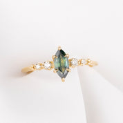 Gold ring with a green gemstone and smaller diamonds on a white background