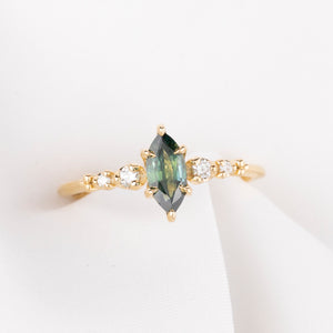 Gold ring with a green gemstone and smaller diamonds on a white background