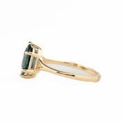 Gold ring with a green gemstone on a white background - side view