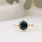 Gold ring with a green gemstone on a light background