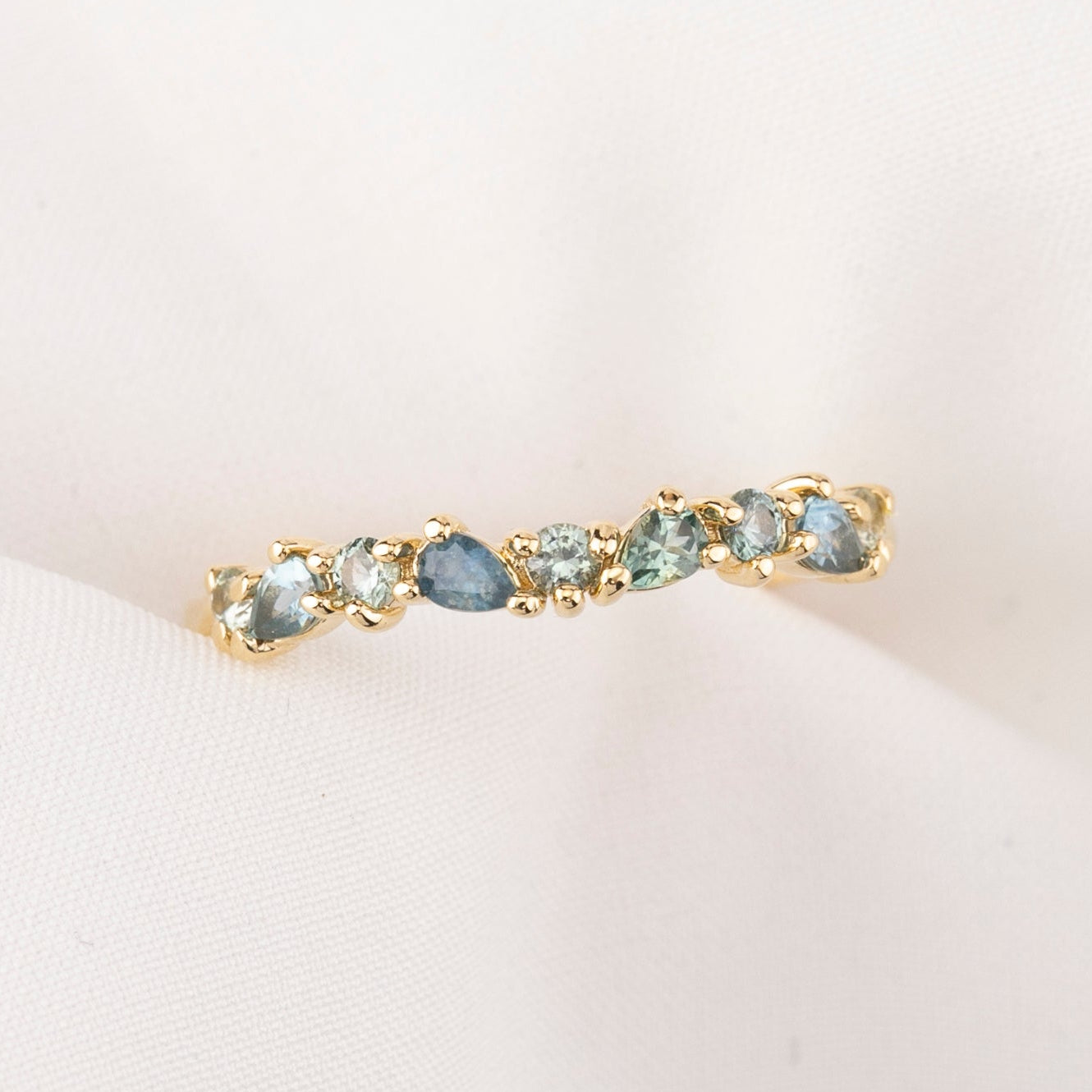 Gold ring with green gemstones on a light pink background