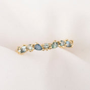 Gold ring with green gemstones on a light pink background