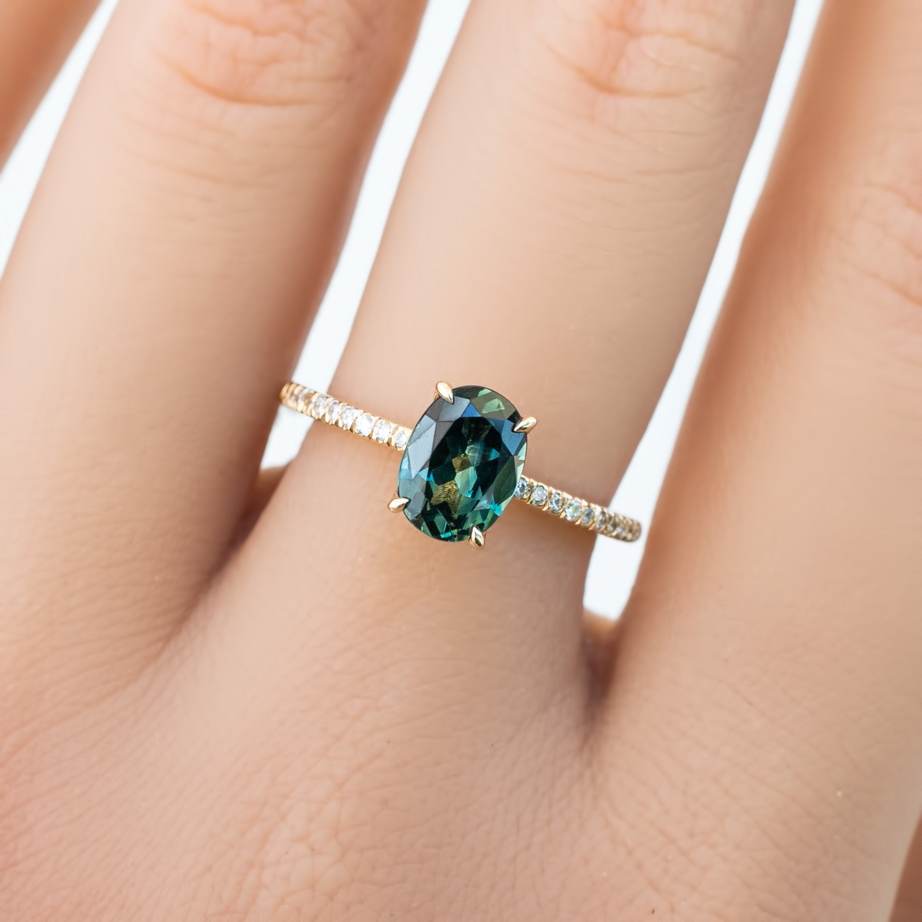 Oval green Queensland sapphire ring 1.53ct with diamond accents in 14k yellow gold on finger