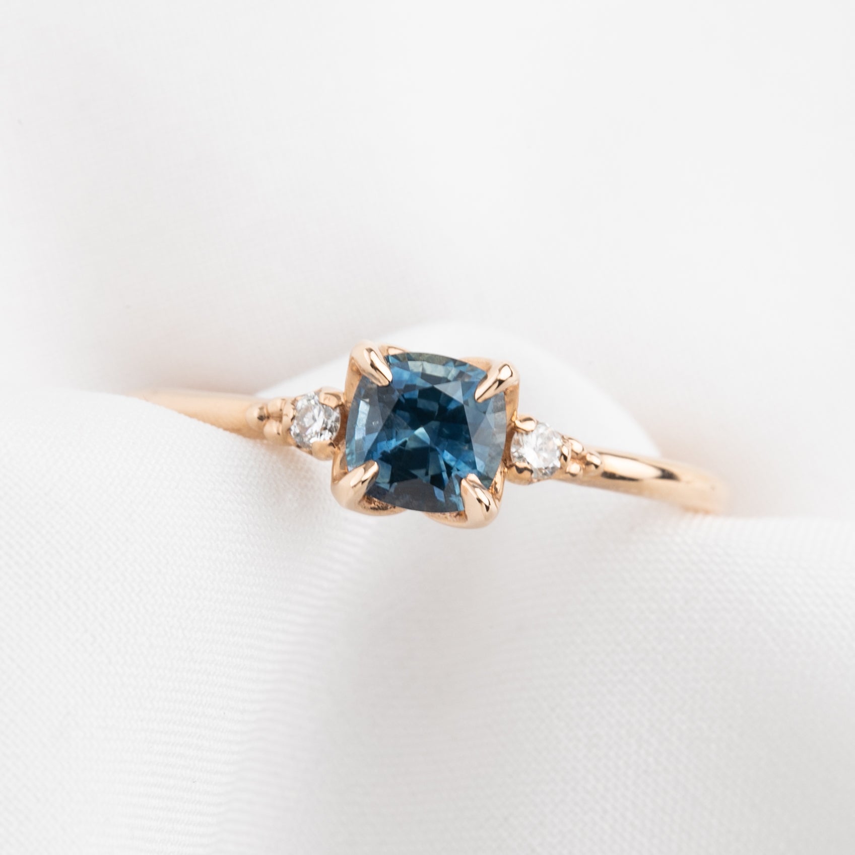 Close-up of Estel Ring featuring 0.76ct cushion Montana sapphire with natural accent diamonds in 14k rose gold band