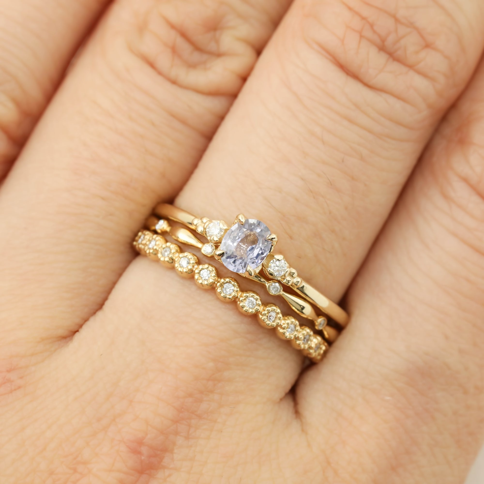 Estel Ring featuring a 0.40ct light blue unheated oval sapphire and 14k gold diamond accents stacked with 2 natural diamond yellow gold bands