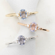 Three 'Estel Rings' with oval-shaped sapphires, in settings of 14k rose gold, 14k white gold, and 14k yellow gold, displayed against a light background., oval shape gemstone