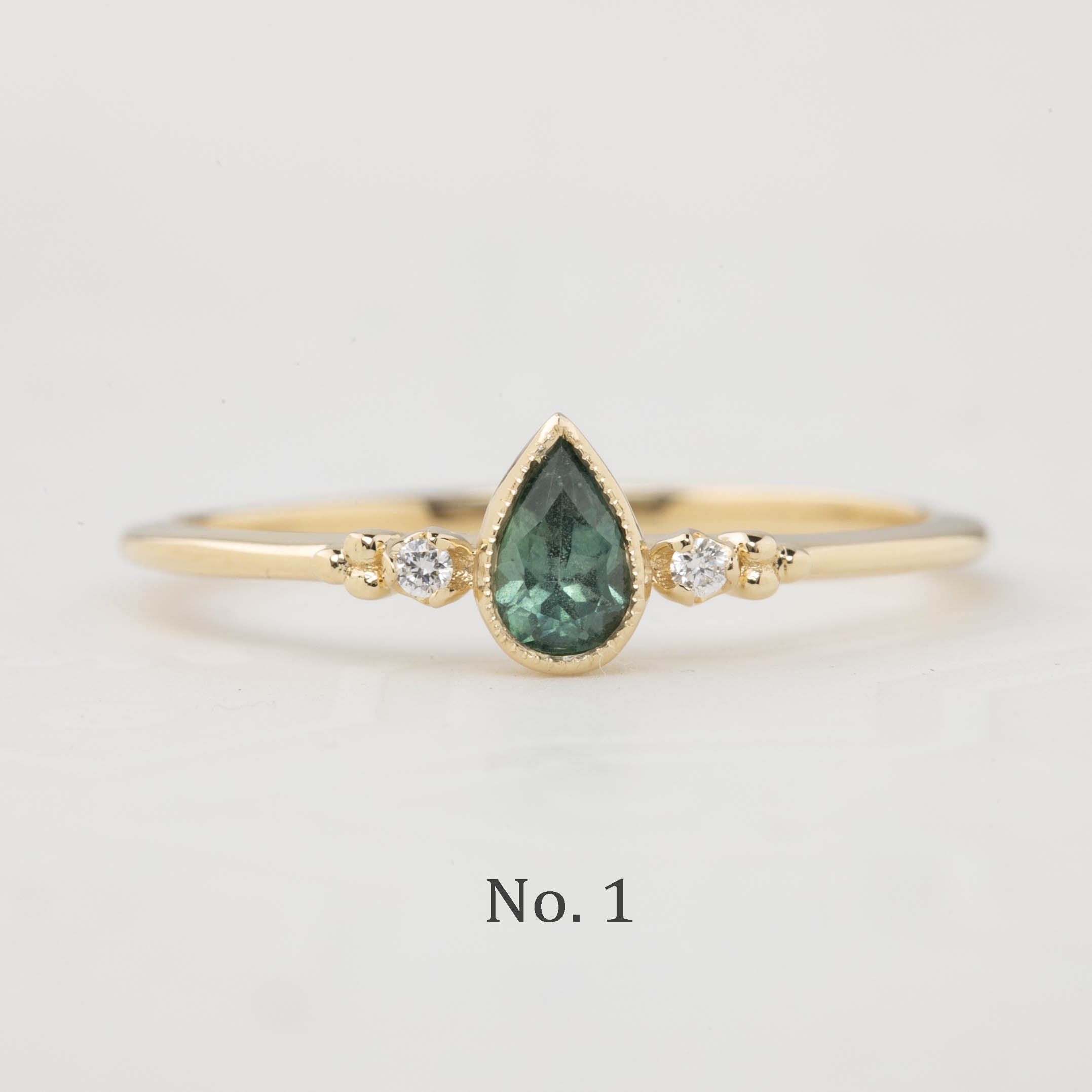 Estel Bezel Ring with a 0.35ct unheated teardrop sapphire and two natural diamond accents in 14k gold.