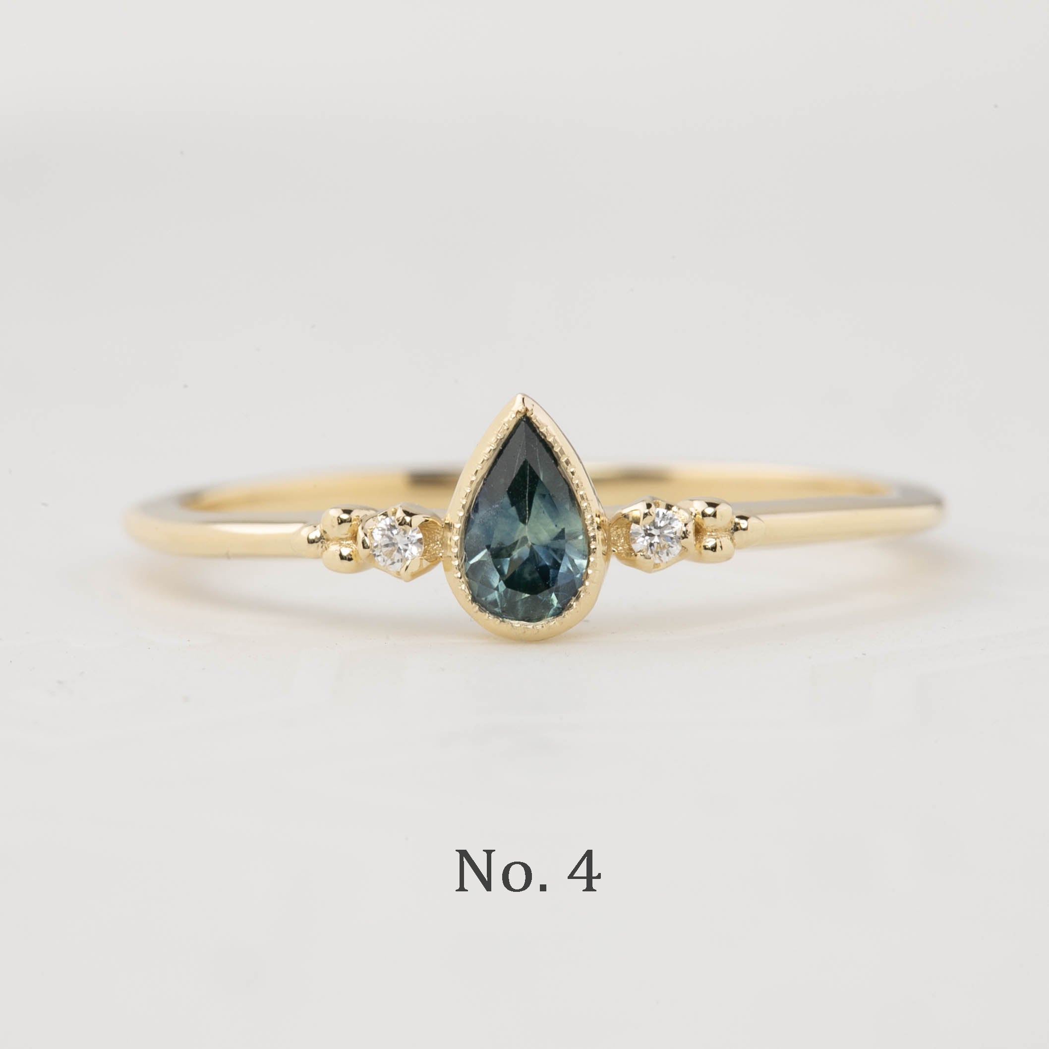 Estel Bezel Ring with a 0.35ct unheated teardrop sapphire and two natural diamond accents in 14k gold.