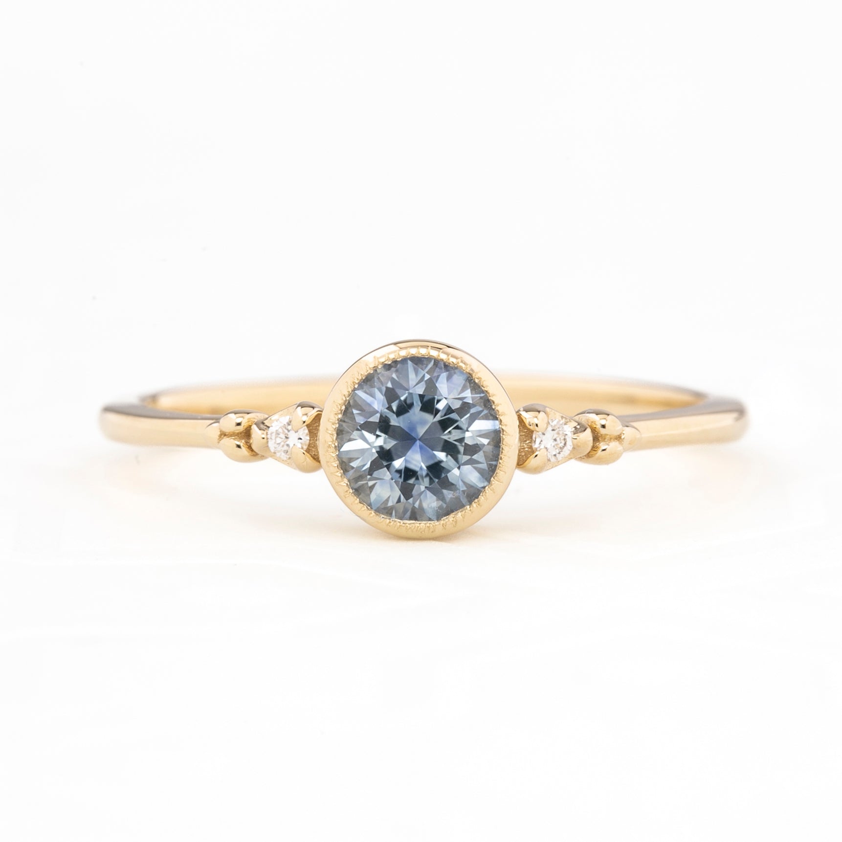 Gold ring with a central blue gemstone on a white background