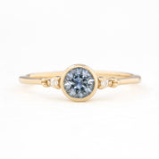 Gold ring with a central blue gemstone on a white background
