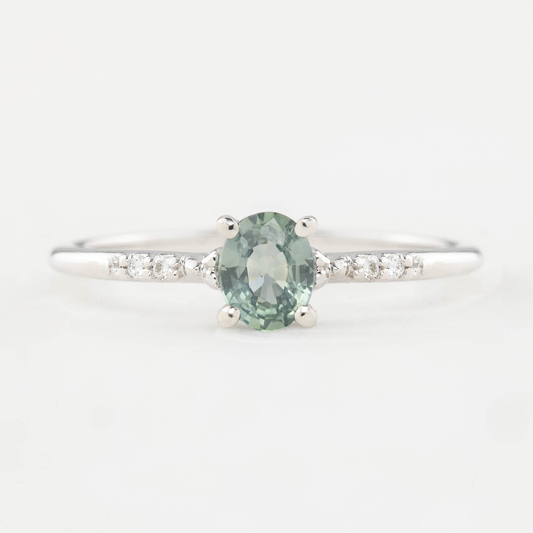 A 0.45ct unheated oval sapphire set in 14k gold with a sparkling diamond pave band.