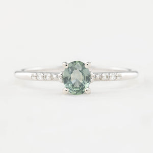 A 0.45ct unheated oval sapphire set in 14k gold with a sparkling diamond pave band.