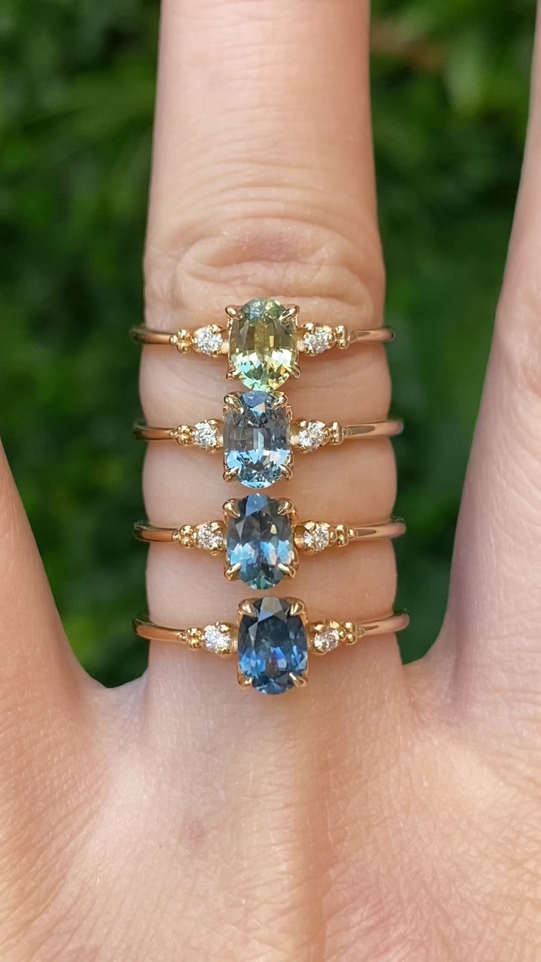 Four rings. Four rings. Different shades of blue green Montana sapphire set in 14k yellow gold with natural diamond accents.