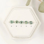 Hexagonal jewelry display with green gemstones labeled A to E on a white background