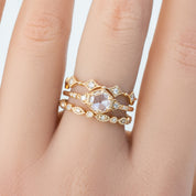 Close-up of a hand wearing a gold art-deco style ring with natural white diamonds and milgrain detailing.