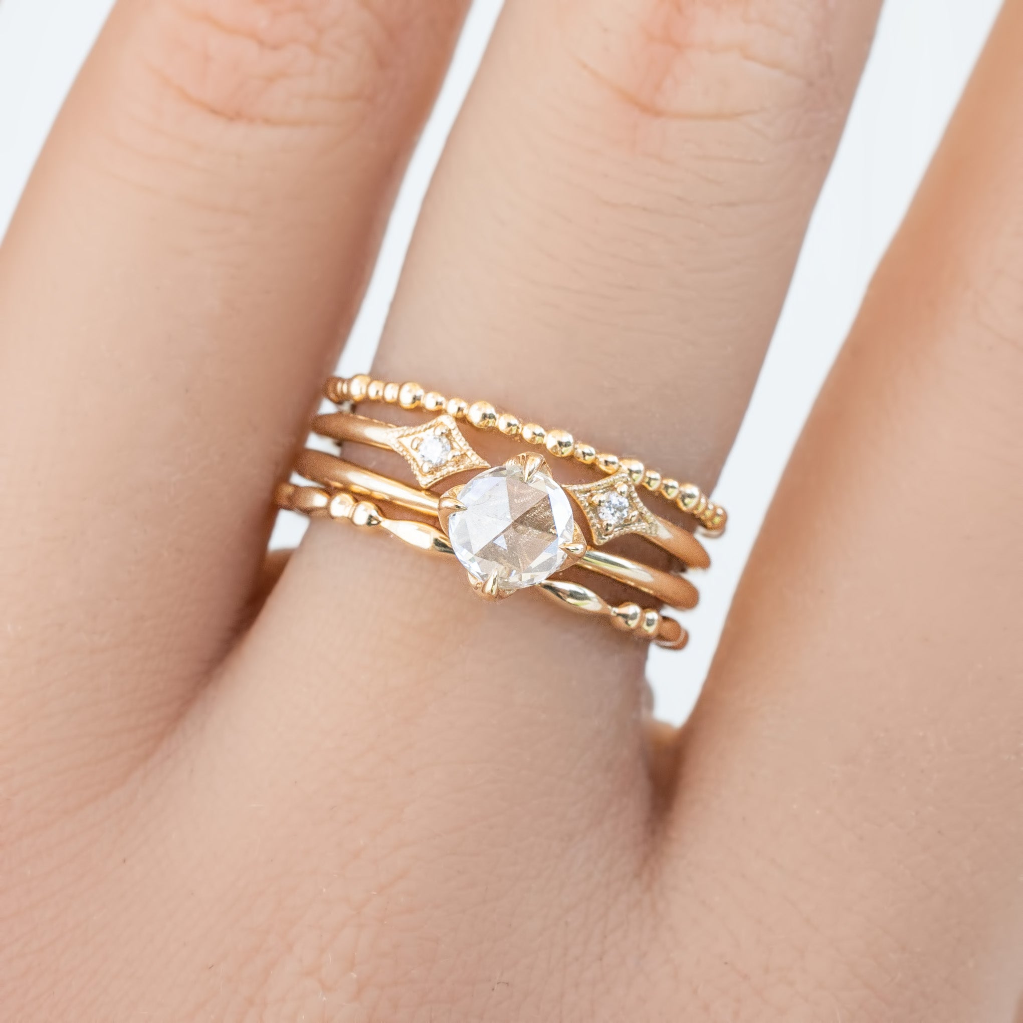 Close-up of a hand wearing a full eternity style bead Gemma Ring in ethically sourced solid gold with diamond accents.
