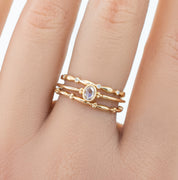 Close-up of a hand wearing a solid gold Julia Ring with intricate bead details and a central oval gemstone.