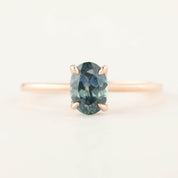 Delicate rose gold ring with a 1.00ct oval teal blue Montana sapphire in a high profile flower setting