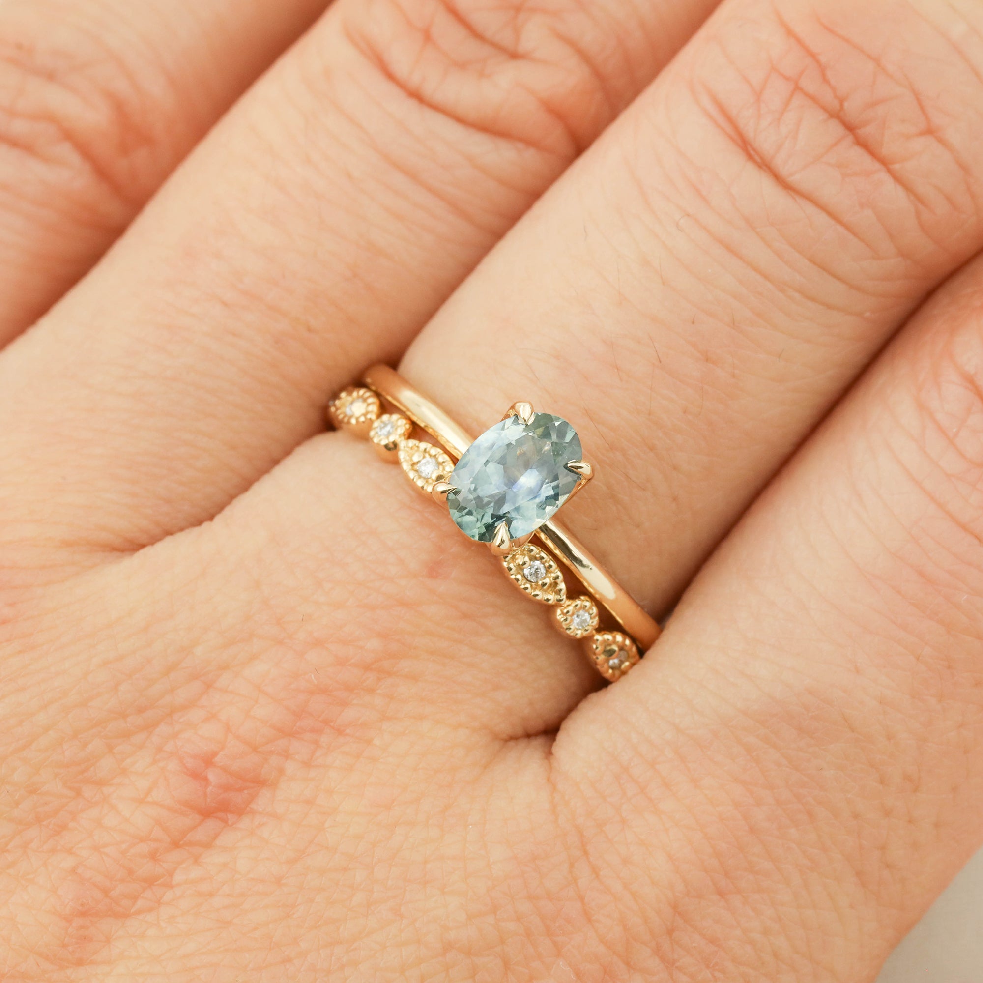 Close-up of a 1.00ct parti blue green Montana sapphire ring set in 14k yellow gold with a flower-inspired setting.