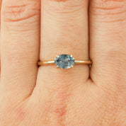 14k yellow gold ring with 1.12ct light blue-green Montana sapphire in classic four-prong setting on finger.
