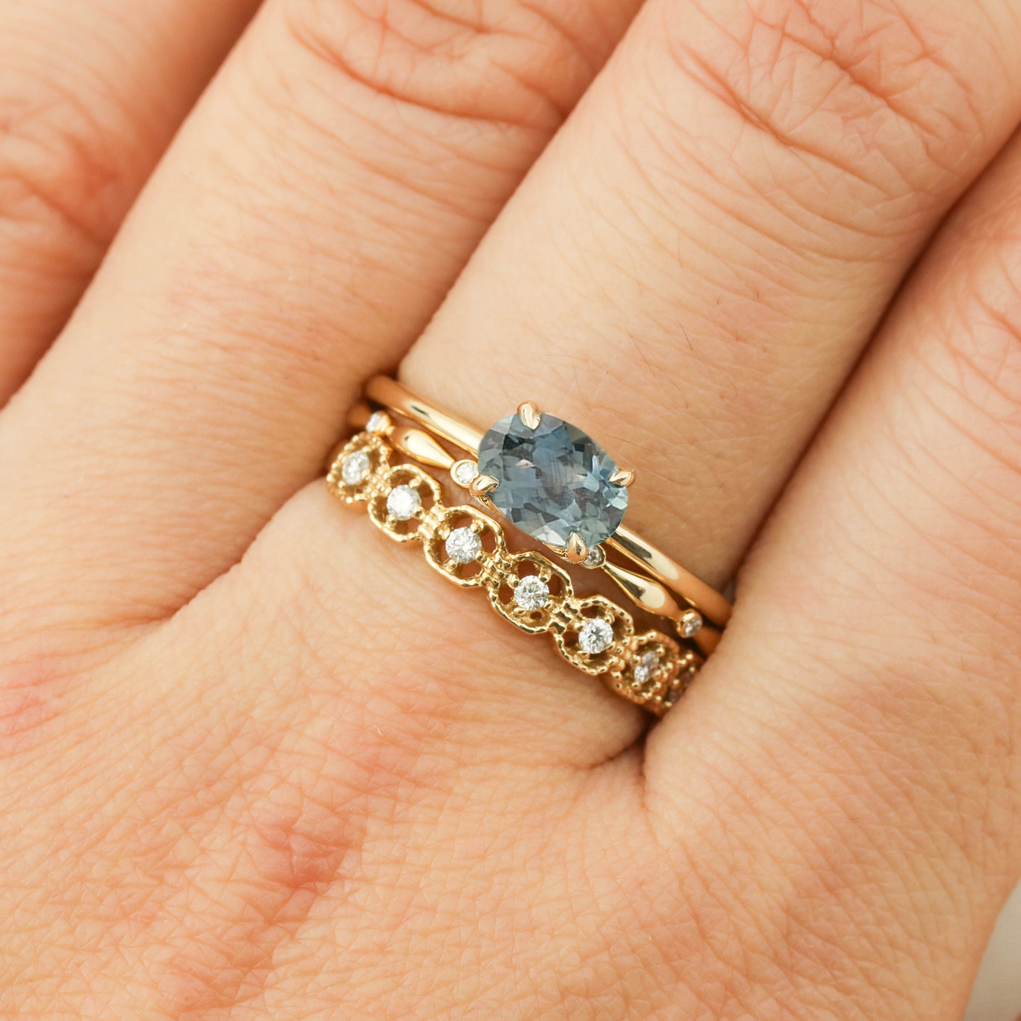 Close-up of hand wearing Sara Ring with 1.12ct blue green Montana Sapphire in 14k yellow gold setting